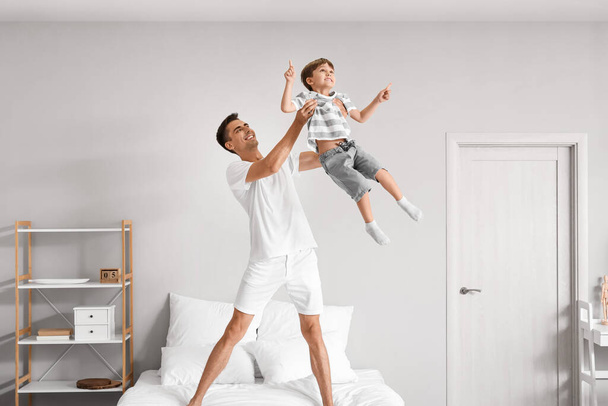 Man and his little son playing in bedroom - Фото, зображення