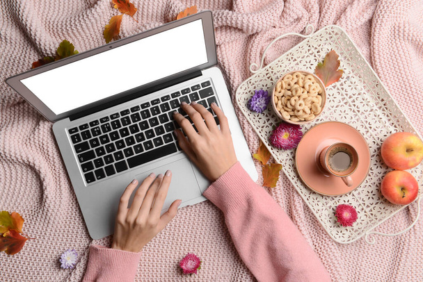 コーヒー、食べ物、秋の葉やピンクの生地の背景にラップトップを使用して花のカップを持つ女性 - 写真・画像