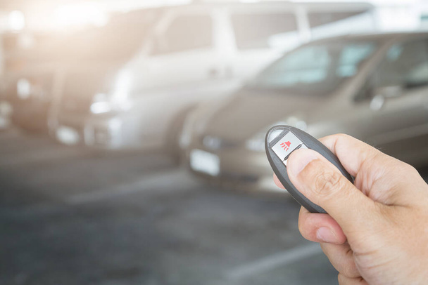 Hand holding car key remote at car park background - Φωτογραφία, εικόνα