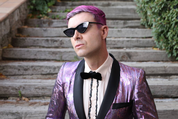 retrato de cerca del joven guapo en chaqueta brillante púrpura y gafas de sol al aire libre - Foto, Imagen