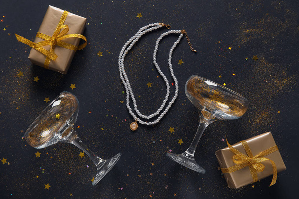 Kompozycja z kieliszkami szampana, pudełkami i pięknym naszyjnikiem na ciemnym tle - Zdjęcie, obraz