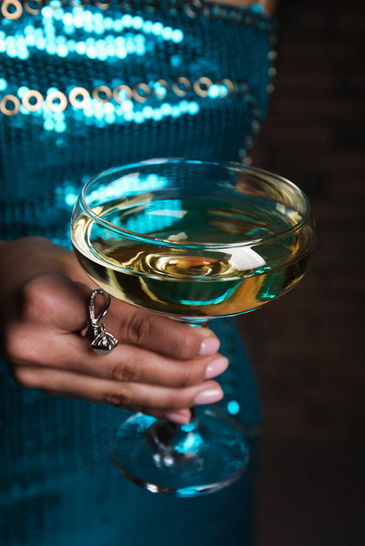 Egy nő gyönyörű ruhában, kezében egy pohár pezsgővel, közelről - Fotó, kép