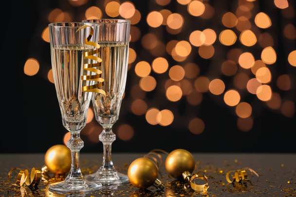 Pohár pezsgő, és karácsonyi golyókat a táblázat világítás homályos ellen - Fotó, kép