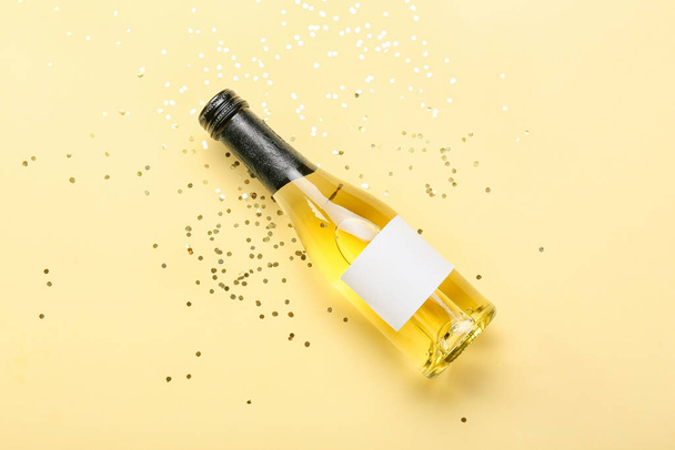 Fles champagne en confetti op kleur achtergrond - Foto, afbeelding