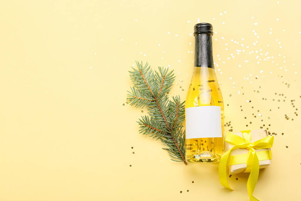 Bottiglia di champagne con ramo di abete e regalo su sfondo a colori - Foto, immagini