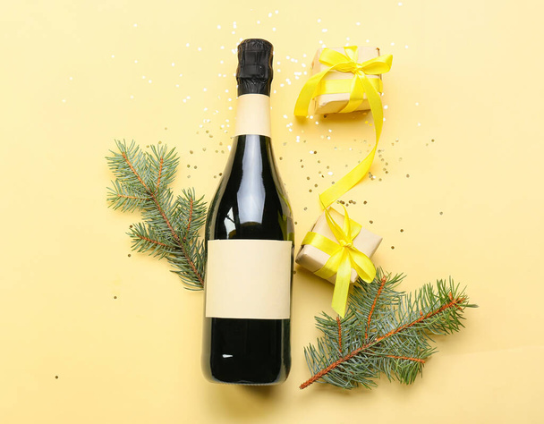 Bottle of champagne with fir branches and gifts on color background - Фото, зображення