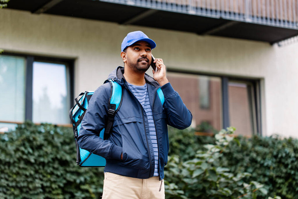 indian delivery man with bag calling on smartphone - Zdjęcie, obraz