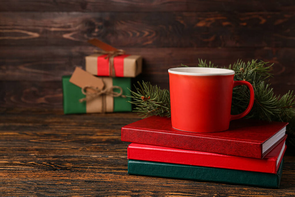Cup of tasty coffee, books and fir branches on wooden background - Photo, Image