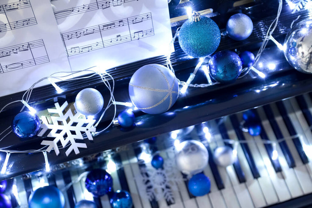 Klavír s krásným vánočním dekorem, svítící světla a poznámkové bloky, detailní záběr - Fotografie, Obrázek