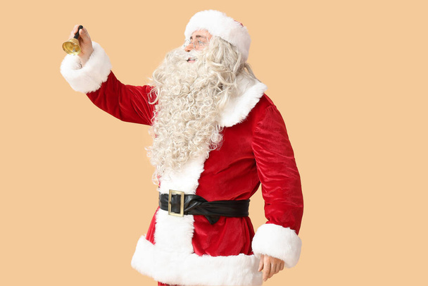 Weihnachtsmann mit Weihnachtsglocke auf beigem Hintergrund - Foto, Bild