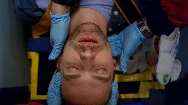 Lekarze pogotowia ratunkowego w rękawiczkach udzielających pierwszej pomocy człowiekowi na noszach - Zdjęcie, obraz