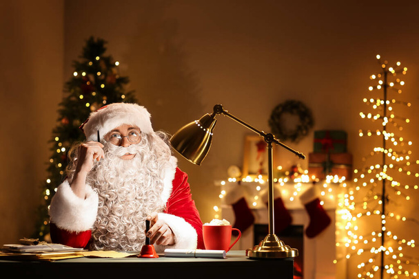 Noel çanı çalan Noel Baba geceleri odada oturuyor. - Fotoğraf, Görsel
