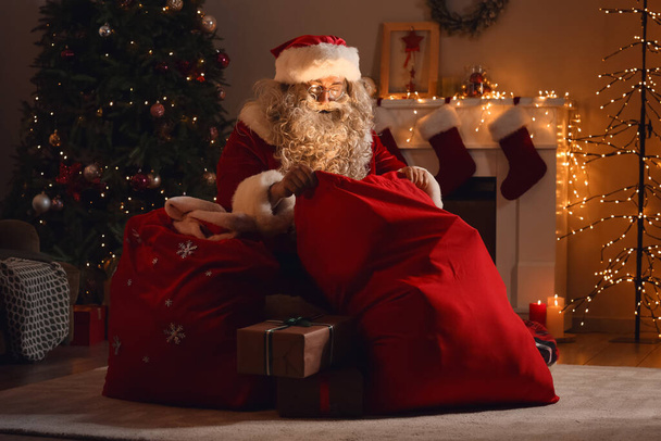 Santa Claus with bag in room at Christmas night - Photo, Image