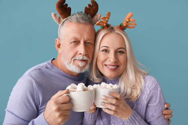 Feliz pareja madura con chocolate caliente en el fondo de color - Foto, imagen