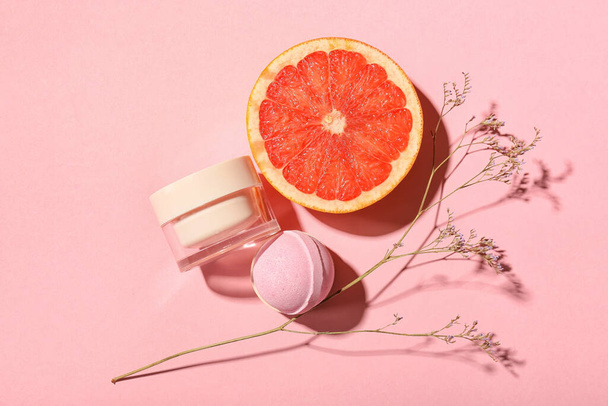 Bomba de baño, tarro de producto cosmético, pomelo y flor seca sobre fondo de color - Foto, Imagen