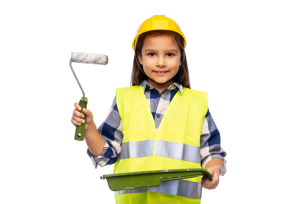 girl in helmet and safety vest with paint roller - Foto, Imagen