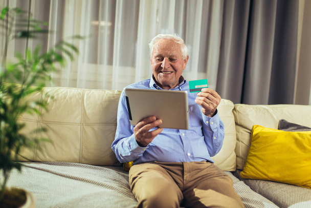 Senior man dziadek zakupy online z tabletem i kartą kredytową w domu. - Zdjęcie, obraz