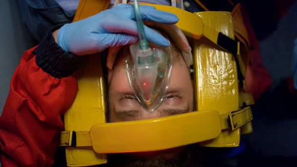 Парамедики доводять першу допомогу людині. Лікарі кладуть кисневу маску на пацієнта
 - Фото, зображення