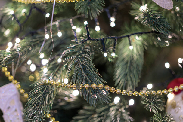 Goldener Kranz am fröhlichen Weihnachtsbaumzweig. Tannenbaumschmuck zum neuen Jahr - Foto, Bild