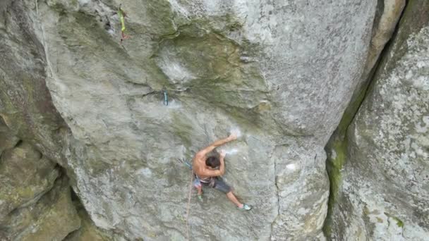 Ισχυρός αρσενικός αναρριχητής σκαρφαλώνει απότομο τοίχο βραχώδους βουνού. Ο αθλητής ξεπερνάει τη δύσκολη διαδρομή. Συμμετέχοντας σε ακραίες αθλητικές έννοια χόμπι - Πλάνα, βίντεο