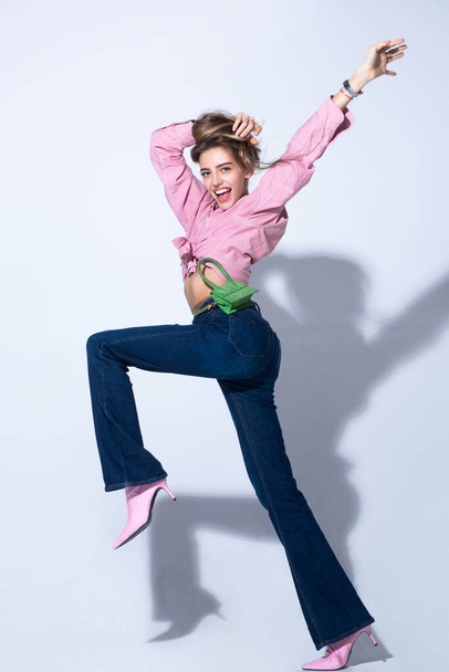 Fashion vrouw in roze shirt en jeans. Bewegingsmodel. Jonge glamour vrouw draagt stijlvolle mode jurk. Modemodel in studio, volledige lengte. - Foto, afbeelding