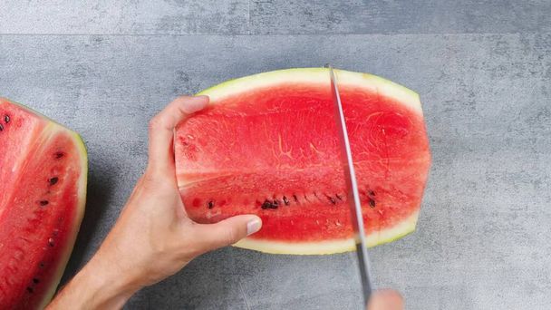 We cut the watermelon into small square pieces with a knife. - Фото, изображение
