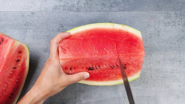 We cut the watermelon into small square pieces with a knife. - Foto, immagini