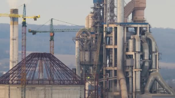 Zeitrahmen eines Zementwerks mit hoher Fabrikstruktur und Turmdrehkränen im Industriegebiet. Fertigung, globale Industrie und Luftverschmutzungskonzept - Filmmaterial, Video