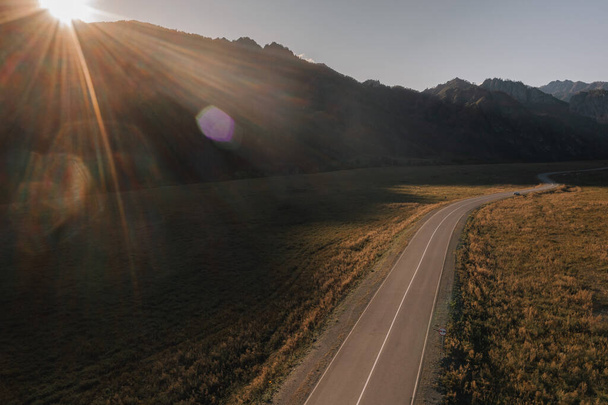 View from a drone asphalt road among the mountains at sunset in Altai - Photo, Image