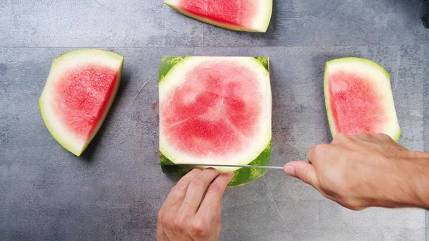 Red watermelon, cut into square slices, laid out on a plate on a white background - Фото, изображение