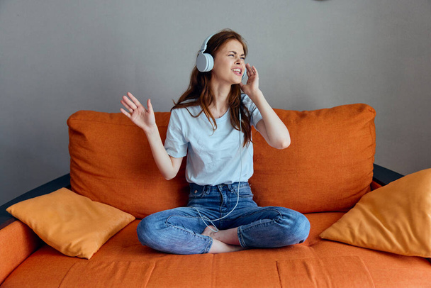 гарна жінка слухає музику з навушниками на помаранчевому дивані
 - Фото, зображення