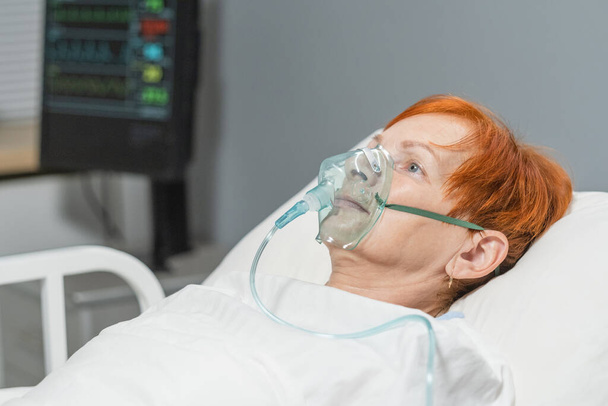 Elderly woman lying in oxygen mask at hospital - Фото, зображення