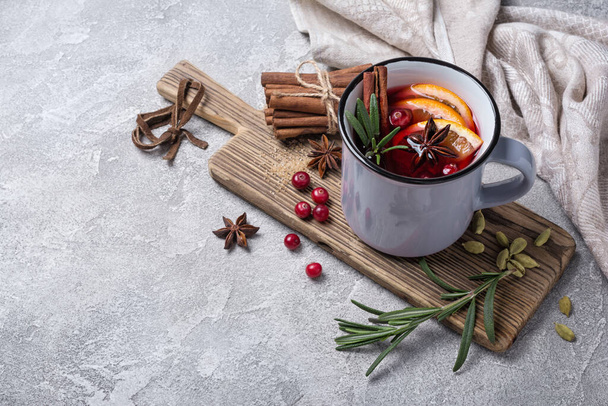 Autumn or christmas traditional drink with oranges, cranberry, cinnamon, rosemary and other ingredients on grey concrete background - Фото, изображение