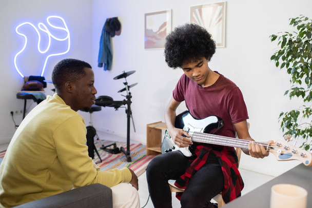Учитель музыки консультирует парня с гитарой - Фото, изображение