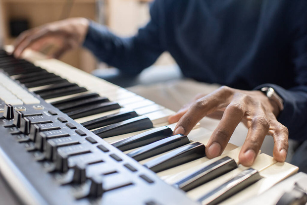Fingers of young African man pressing keys of music keyboard - Foto, imagen