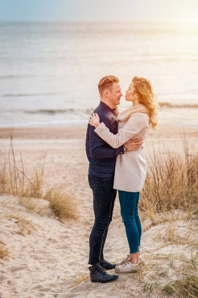 Romantic outdoor fashion portrait of stunning couple in love hugs and posing on the beach at evening, stylish clothes. - Fotó, kép