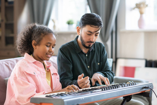 Suloinen koulutyttö ja hänen musiikinopettajansa soittaa piano näppäimistö yhdessä - Valokuva, kuva