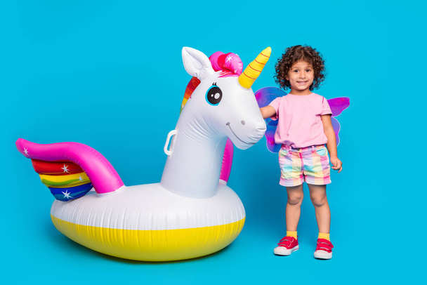 Full length body size view of cute cheerful funky girl with rubber horse rest relax isolated over bright blue color background - Foto, afbeelding