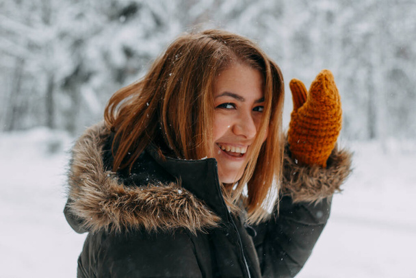 Portrait of a happy girl with a short haircut in mustard mittens in the forest after a snowfall . Christmas holidays, outdoor activities. - 写真・画像