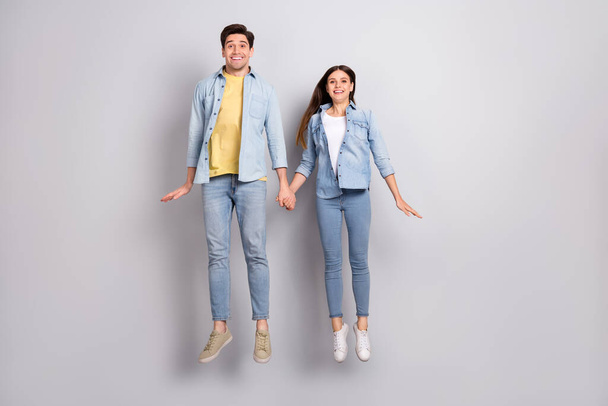 Photo of funny excited lady guy dressed denim shirts holding arms jumping high empty space isolated grey color background - Foto, Imagem