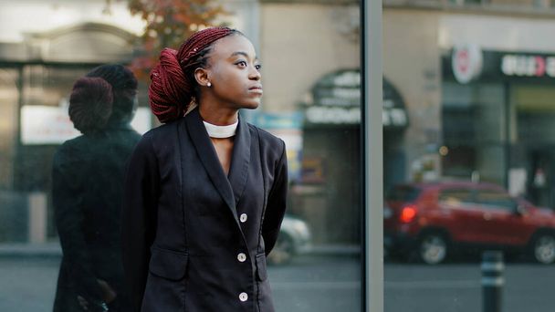 Africký americký stylový módní žena v černém společenském obleku stojí v blízkosti zrcadlové zdi v blízkosti firemní budovy hledá na straně čeká na setkání, smutná osamělá dáma dívka student venku ve městě - Fotografie, Obrázek