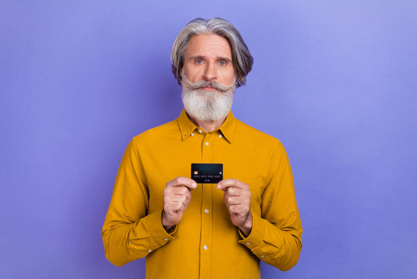 Photo of aged man hold bank card advertise profit recommend decision isolated over purple color background - Φωτογραφία, εικόνα