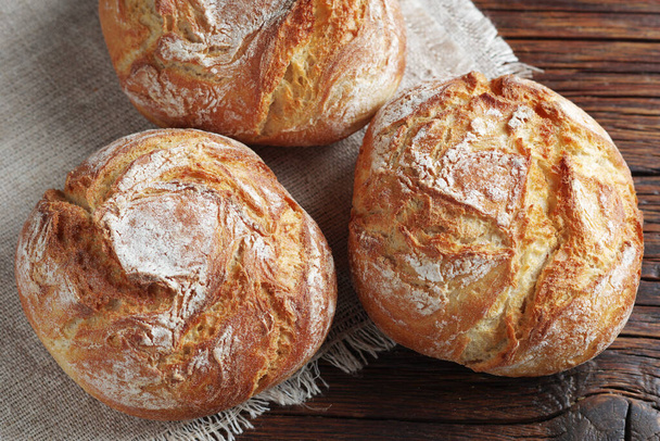 Small loaves of bread on wooden table close-up - Valokuva, kuva