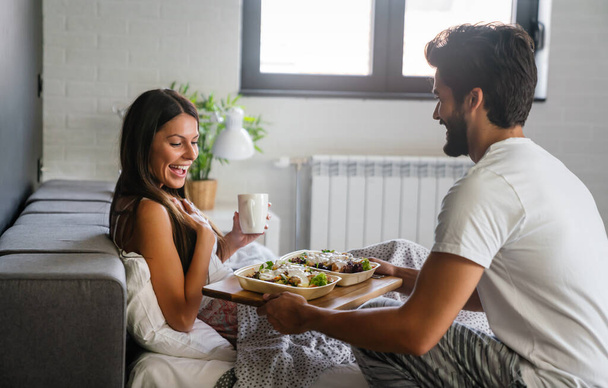 Good morning. Healthy breakfast in bed. Young beautiful couple in love spending time together - Foto, Imagen