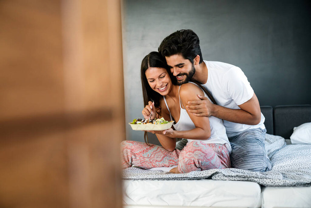 Young caucasian couple having romantic breakfast in bed. - Foto, afbeelding