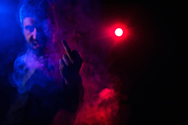Close up photo of man showing middle finger on pink and black background. - Foto, Imagen