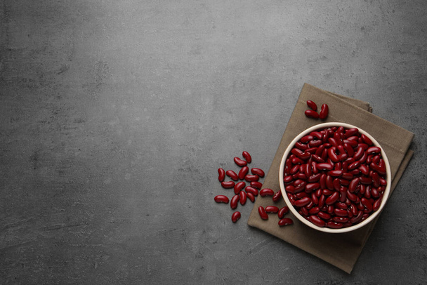 Raw red kidney beans with bowl and napkin on grey table, flat lay. Space for text - Photo, Image