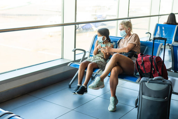 Család a reptéren. Vonzó fiatal nő és aranyos kislánya készen állnak az utazásra. Boldog családi koncepció. - Fotó, kép