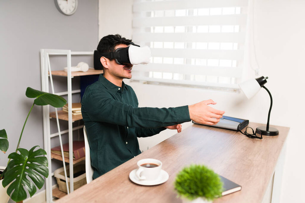 Onnellinen nuori mies kättelee virtuaalista ystävää tai työkaveria toimistossa VR-suojalaseja käytettäessä - Valokuva, kuva