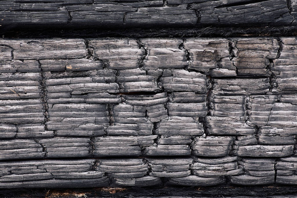 Teksturowane monochromatyczne tło szorstkiego spalonego drewna ciemnego koloru z pęknięciami w rzędach - Zdjęcie, obraz